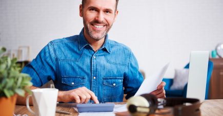 portrait-smiling-man-calculating-his-monthly-expenses